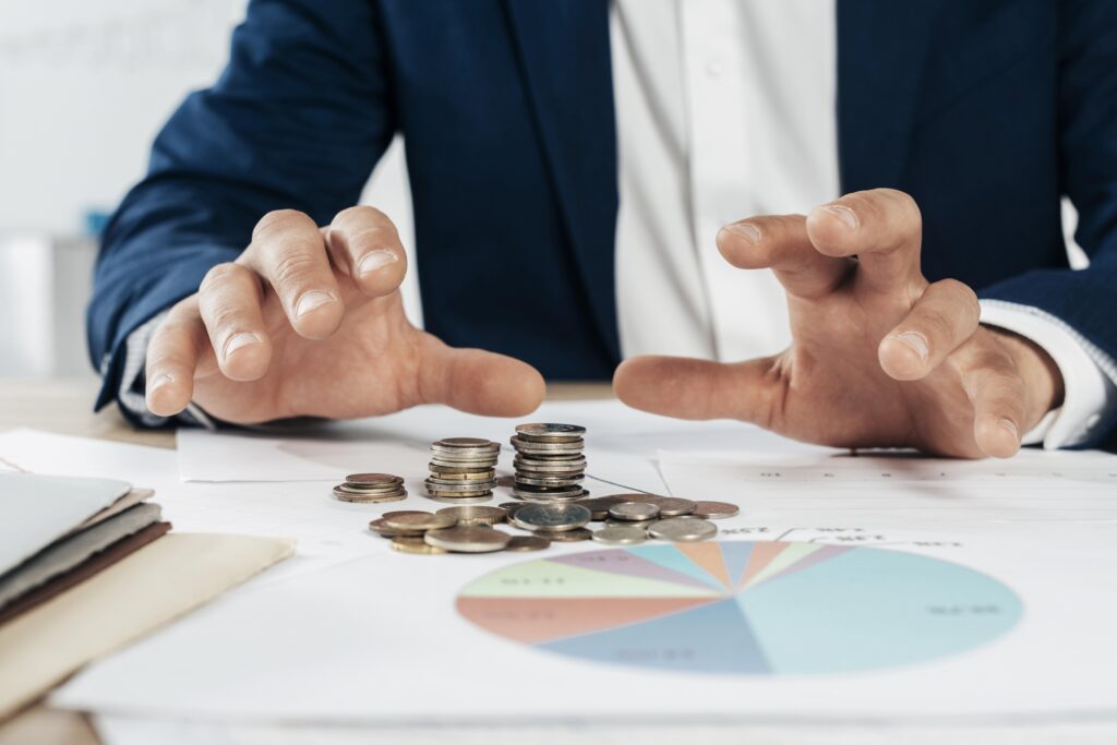 Consultor de subvenciones revisando documentación financiera junto a monedas que simbolizan ayudas económicas